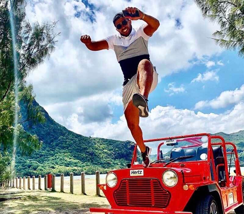 man jumping off the front of vehicle by beach
